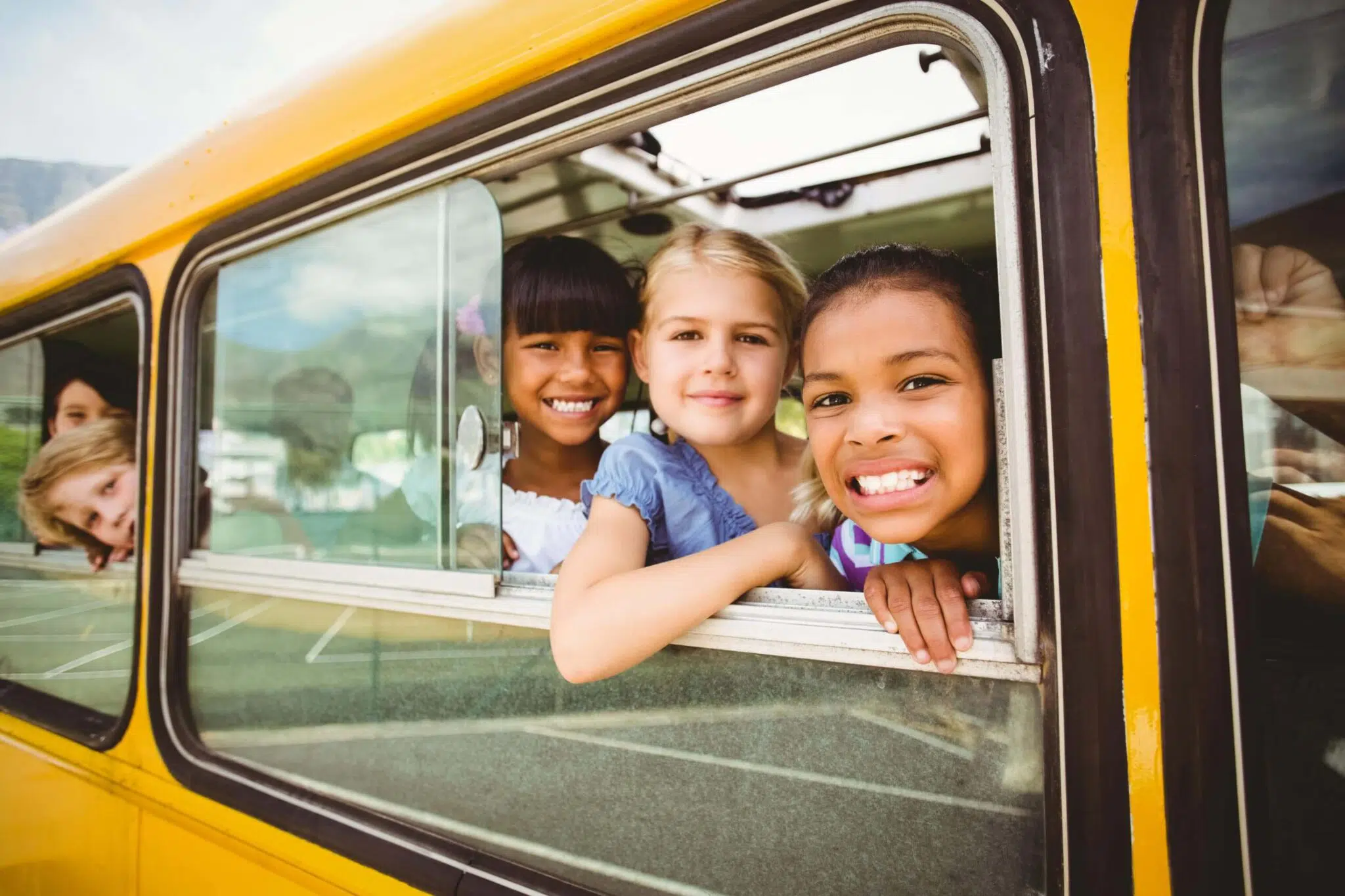 Smiling kids looking out the window on a school bus