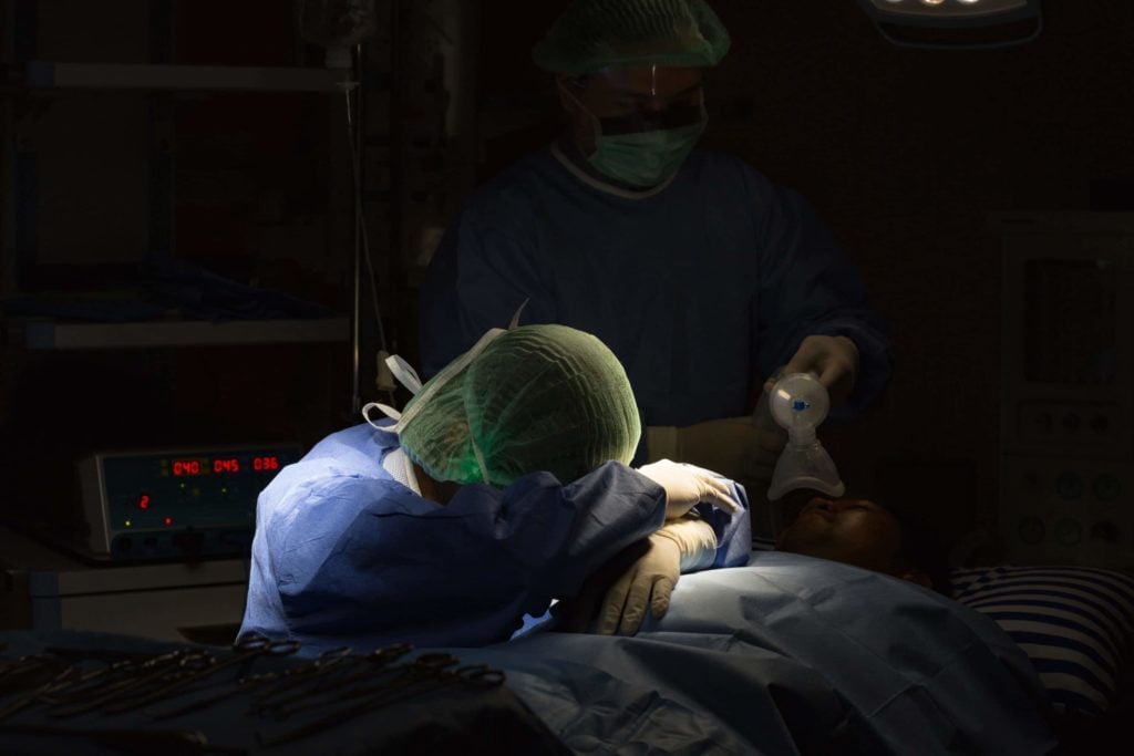 Surgeon resting her head in her arms in a dark surgical room