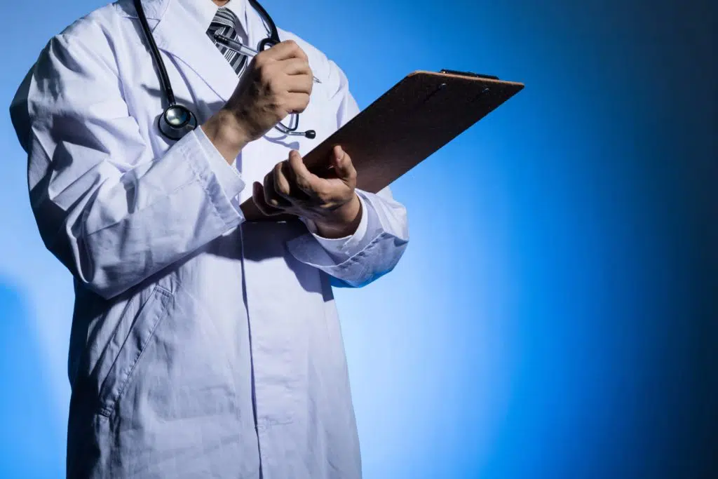 Doctor in a white coat holding clipboard with blue background