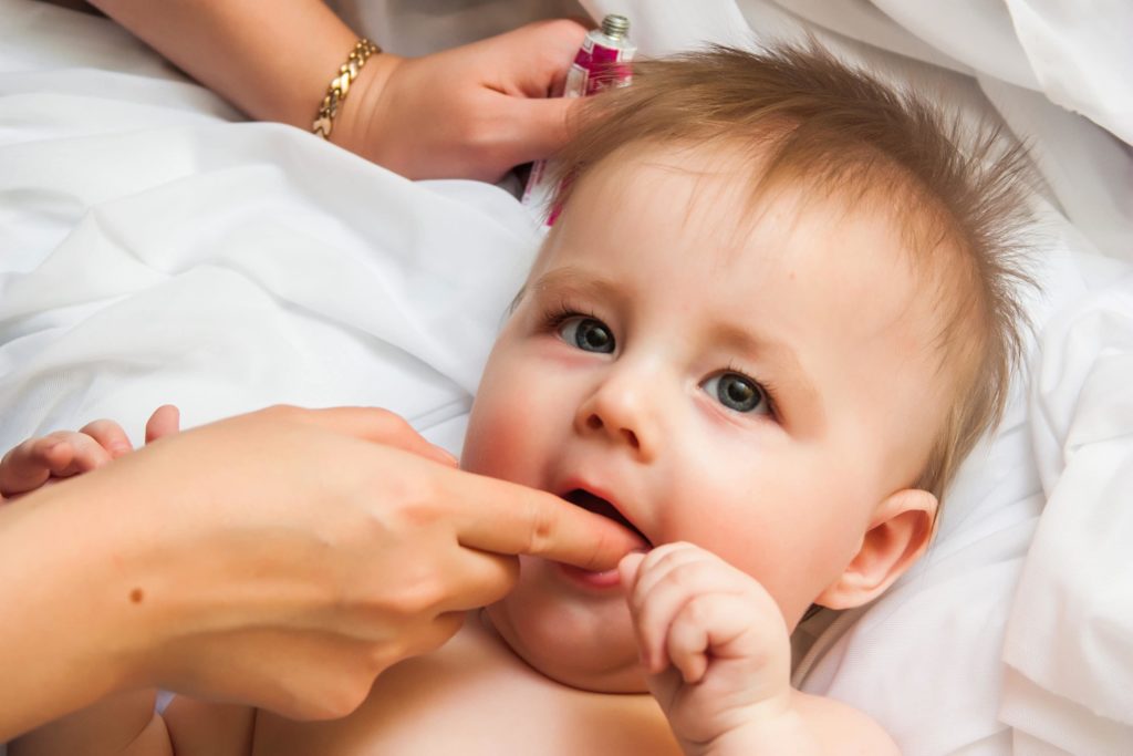 woman applying product to teething baby's gums