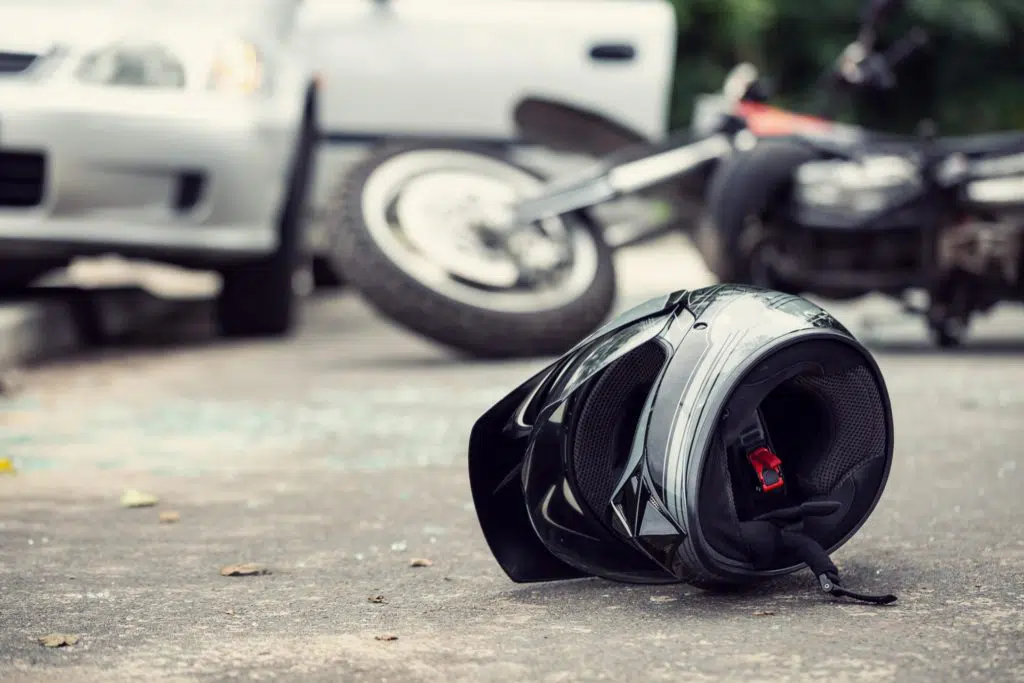 Motorcycle helmet shown in the foreground at the scene of a motorcycle accident with a motor vehicle.
