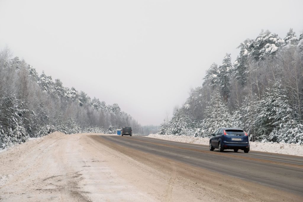 Cars driving down a snowy road in the day time