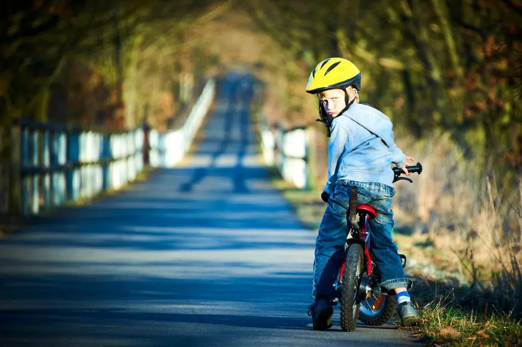 child on a bike looking backward on an open country road
