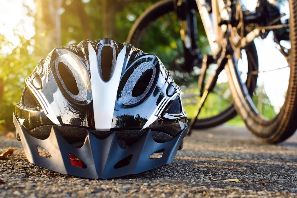 bike helmet in foreground with bicycle in the background and sunshine