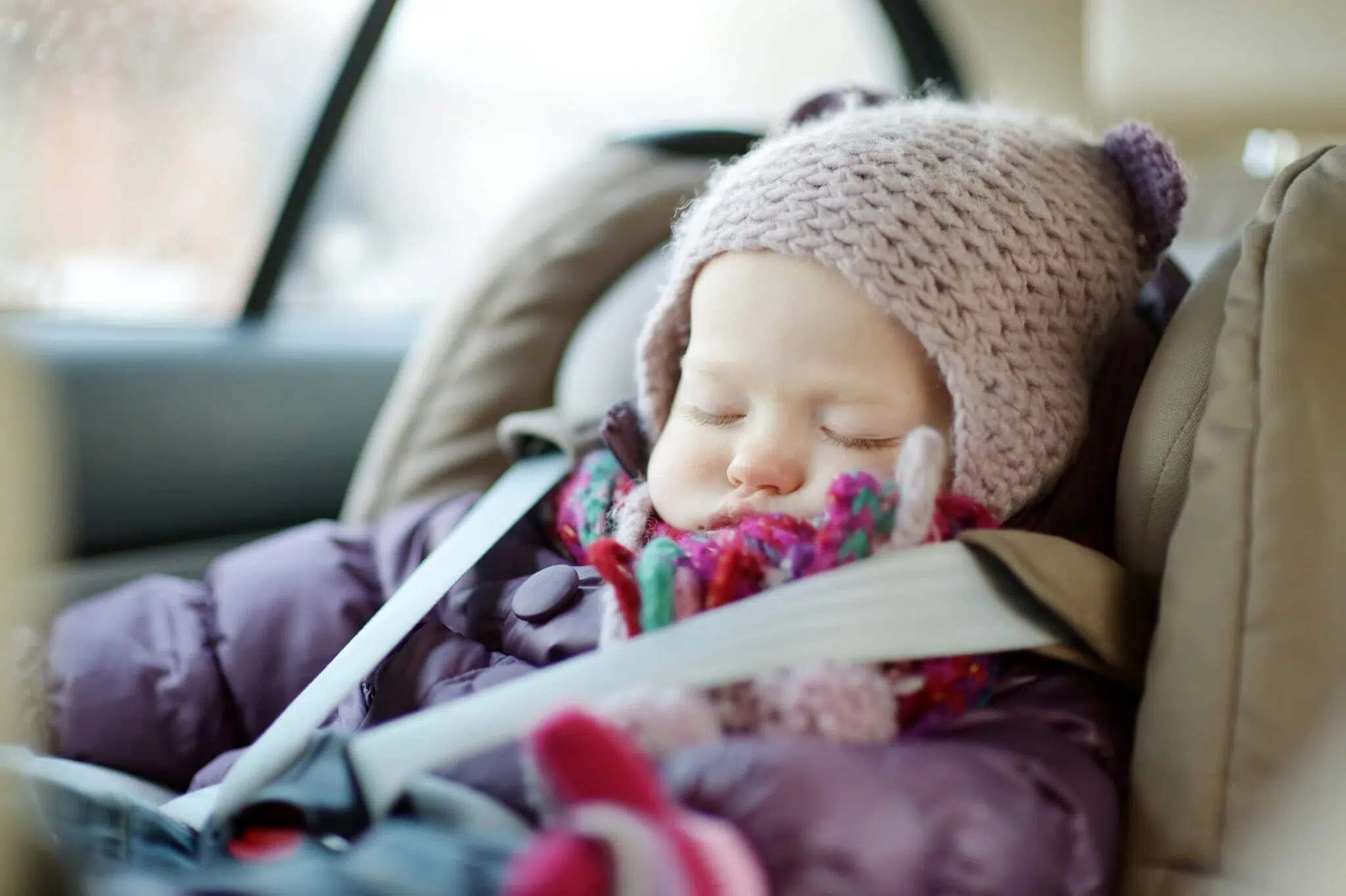 Infant in winter coat and hat in a car seat