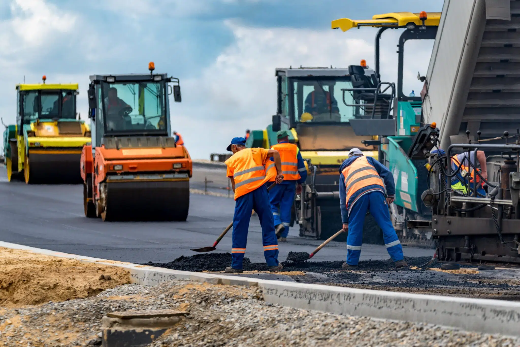 Construction workers at a roadside construction site applying pavement.