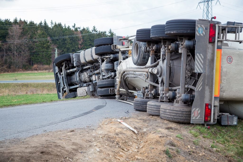 Truck is shown overturned on a highway after an accident.