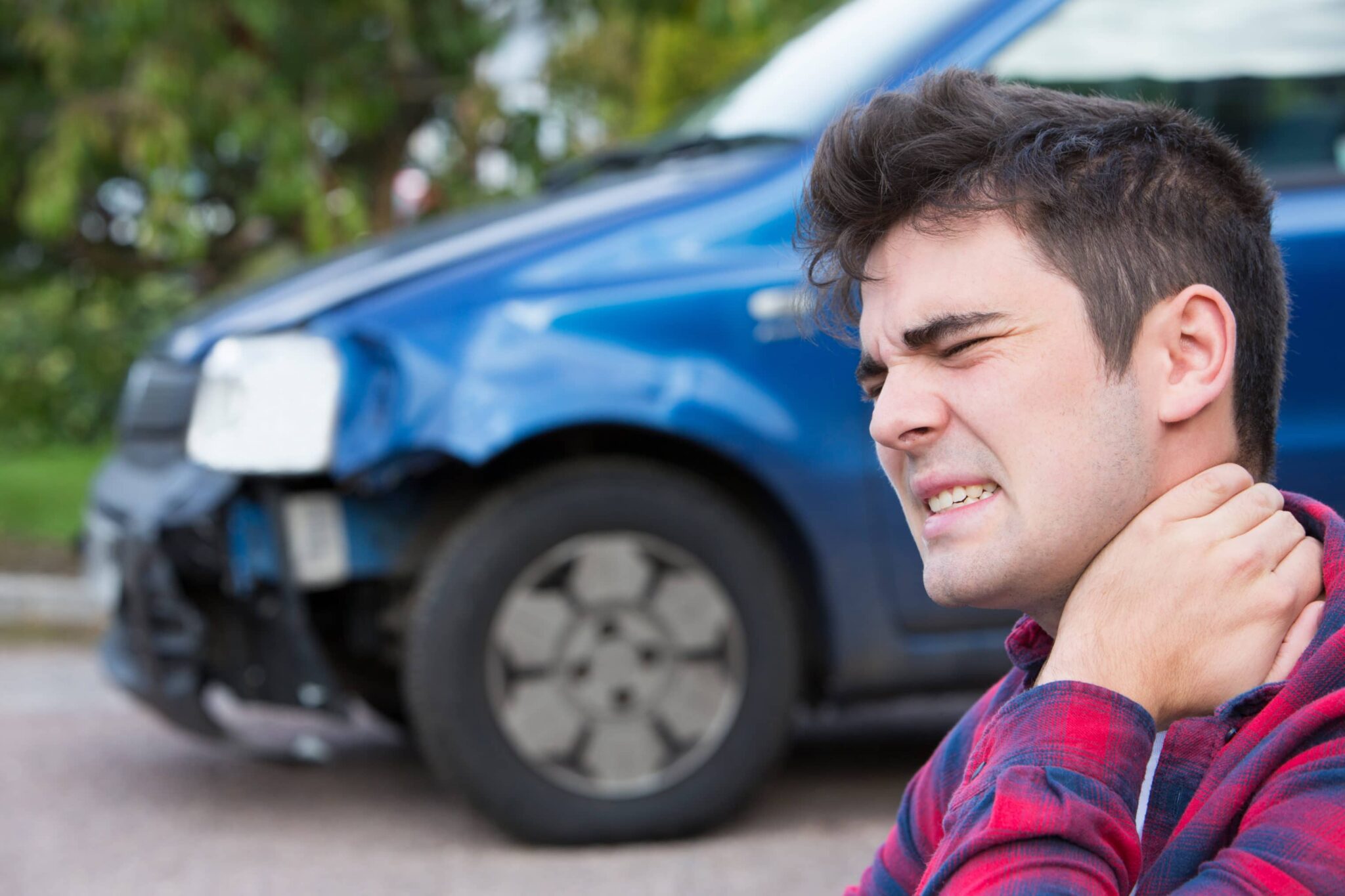 Man holding the back of his neck in pain after a car-crash injury