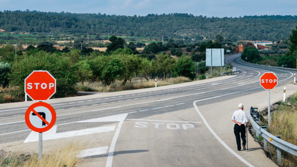 Older gentleman walks along the highway on an open road