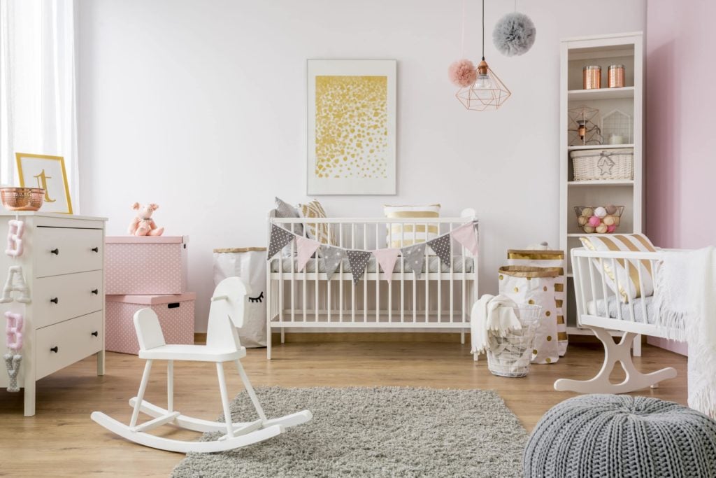 child's room with rocking chair, crib, changing table, and pink and white color scheme.