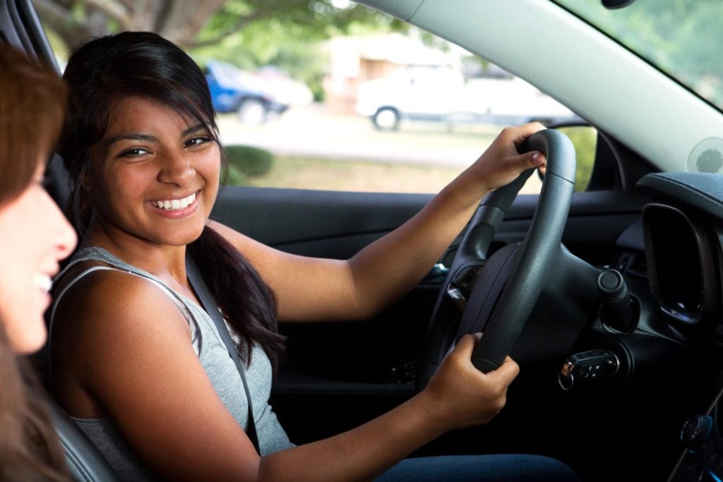 Young woman smiles at her friend from the drivers' seat
