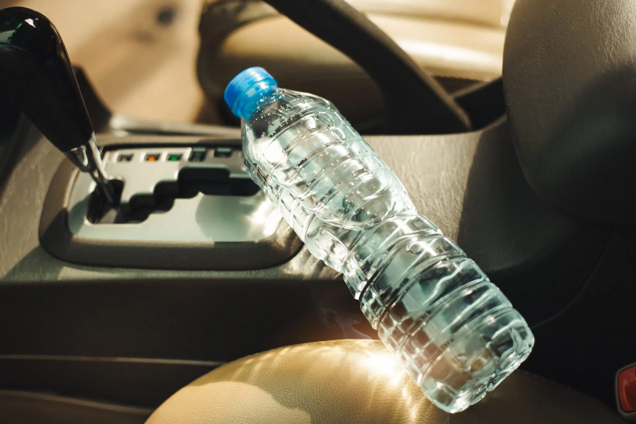 plastic water bottle sits on the gear stick in the car in the sunlight