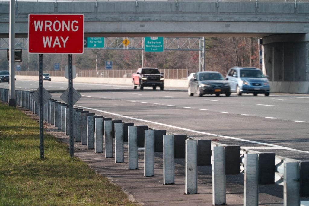 cars drive on a highway with a wrong-way sign in the foreground