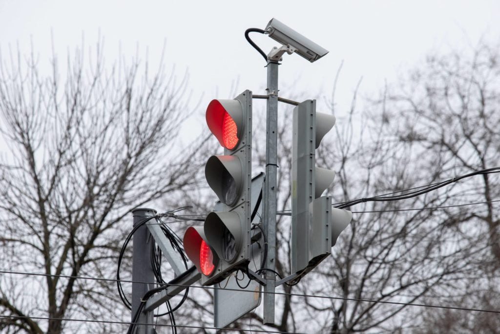 red light camera on top of a red traffic light