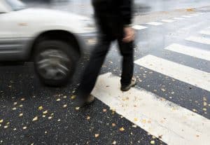 Man on pedestrian crossing in autumn, in danger of being hit by car