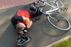 Bicyclist lying on the road and holding his head