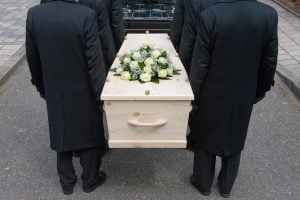Wrongful death case Individuals solemnly transporting a coffin into a vehicle.