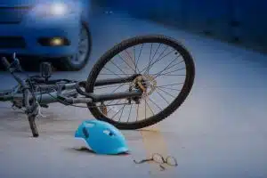 Car and bicycle collision on road at night.