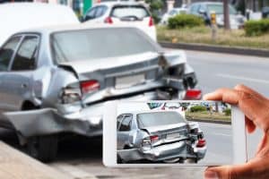 Car insurance agents use smartphones to capture photos of vehicles damaged in accidents as evidence for insurance claims.