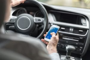 Man using a smartphone while driving a car.