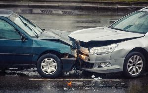 Two cars involved in a head-on collision on a rainy day, causing significant damage.