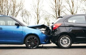Two cars involved in a rear-end collision on a road, showing significant damage.