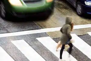 A busy city street crosswalk with people in a hazardous situation.