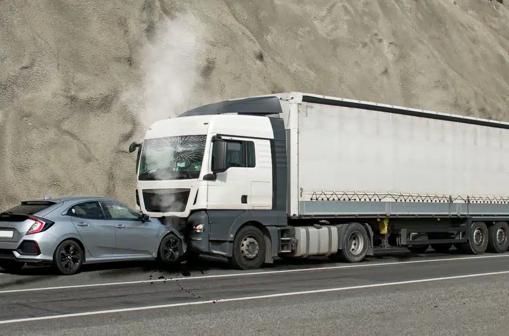 Large truck involved in a collision with a car on a highway.