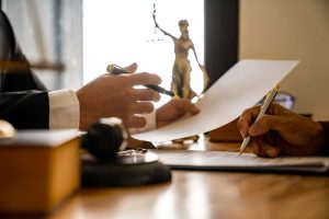 Two people reviewing and signing legal documents at a desk with gavel.