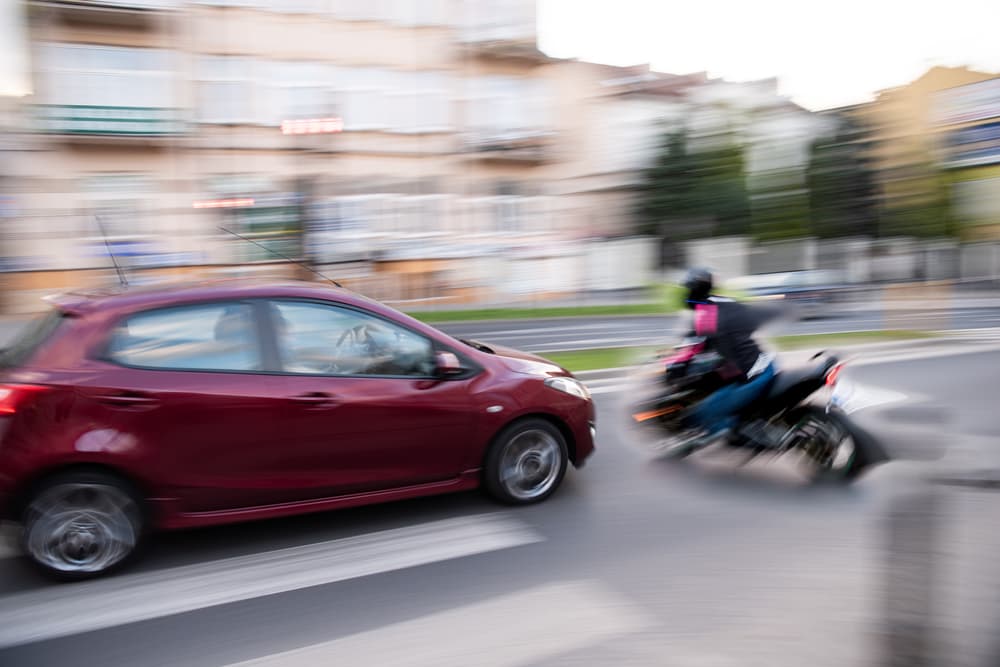 motorcycle is near collision with a speeding car