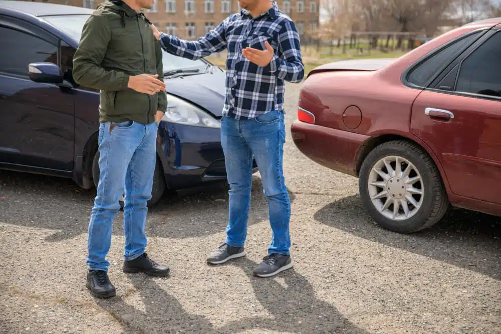 Two men arguing after a car accident on the road