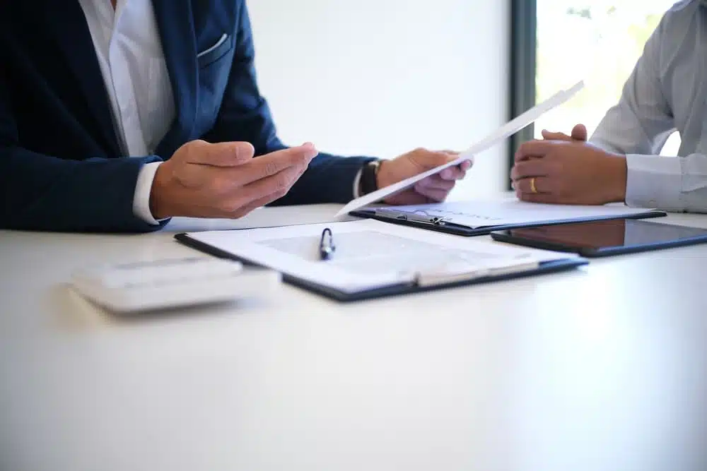 Two individuals discussing legal documents at a table, focusing on building a strong partial-fault claim.