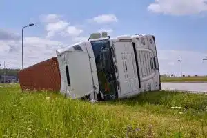 Overturned flatbed truck lying on its side off a roadway, indicating a serious truck accident.