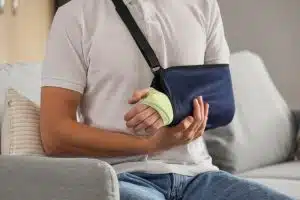 Injured young man after accident sitting on sofa at home, closeup