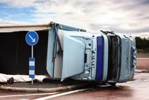 Overturned truck near road sign, illustrating complex scenarios in trucking accidents and shared fault cases.