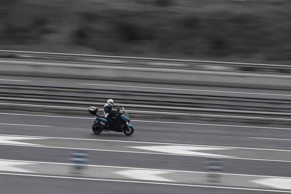 Motorcycle riding along a busy highway, illustrating the risks riders face from traffic and road hazards on routes like the Brooklyn-Queens Expressway.