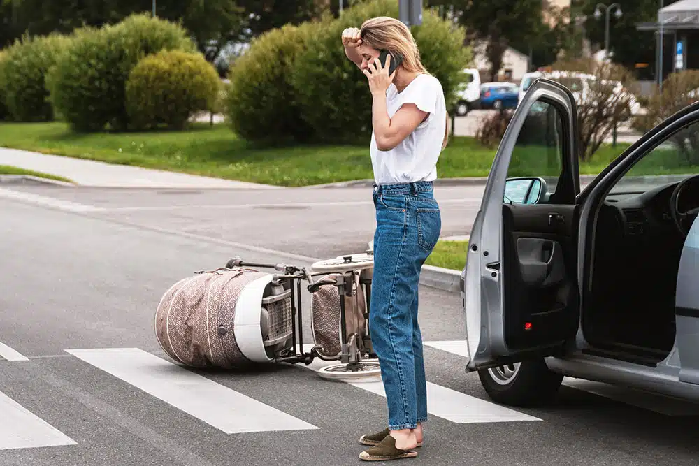 Horrified driver makes an emergency call after a car accident with baby pram on the crosswalk, illustrating pedestrian right-of-way issues in Manhattan crosswalks.