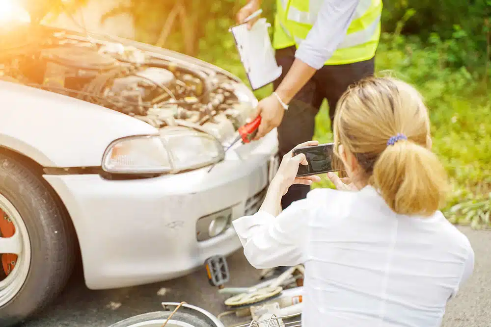 Insurance representative taking photos of car damage with a phone, illustrating how New York’s no-fault rules apply after minor car accidents and insurance claims.