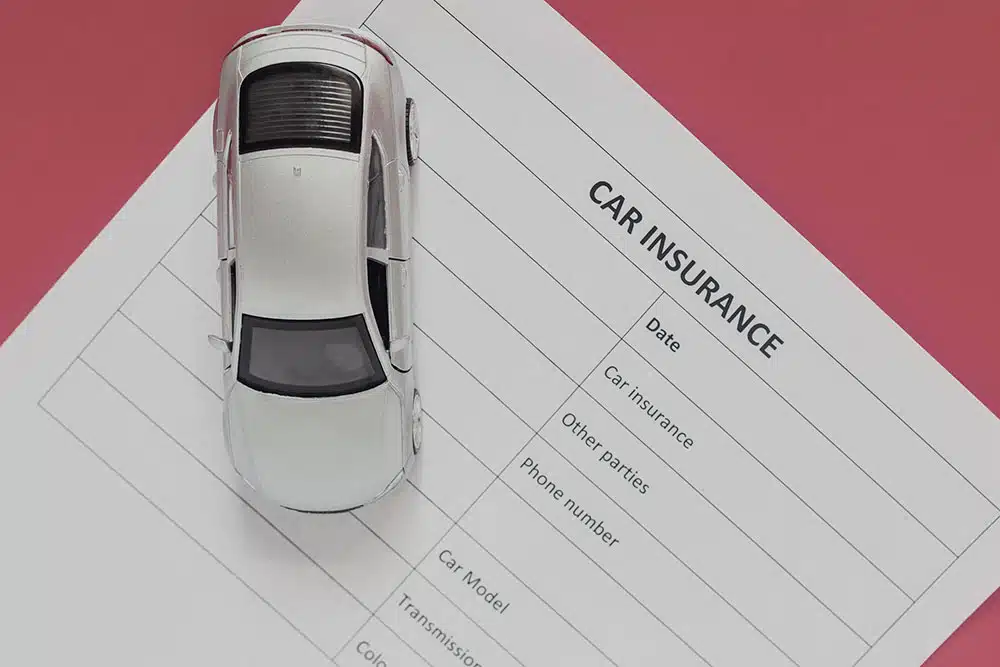 Toy car placed on a motor insurance document, symbolizing New York no-fault coverage for medical bills after minor car accidents.