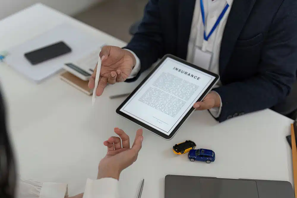 Advisor reviewing an insurance policy with a client on a tablet, illustrating how insurers handle claims and why you must watch what you tell them after an accident.